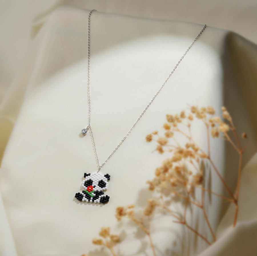 Beaded panda pendant holding a red flower on a silver-tone chain