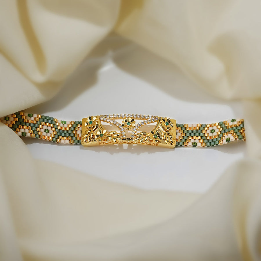 Sage green and gold loom-woven bead cuff with a gold floral centre plate