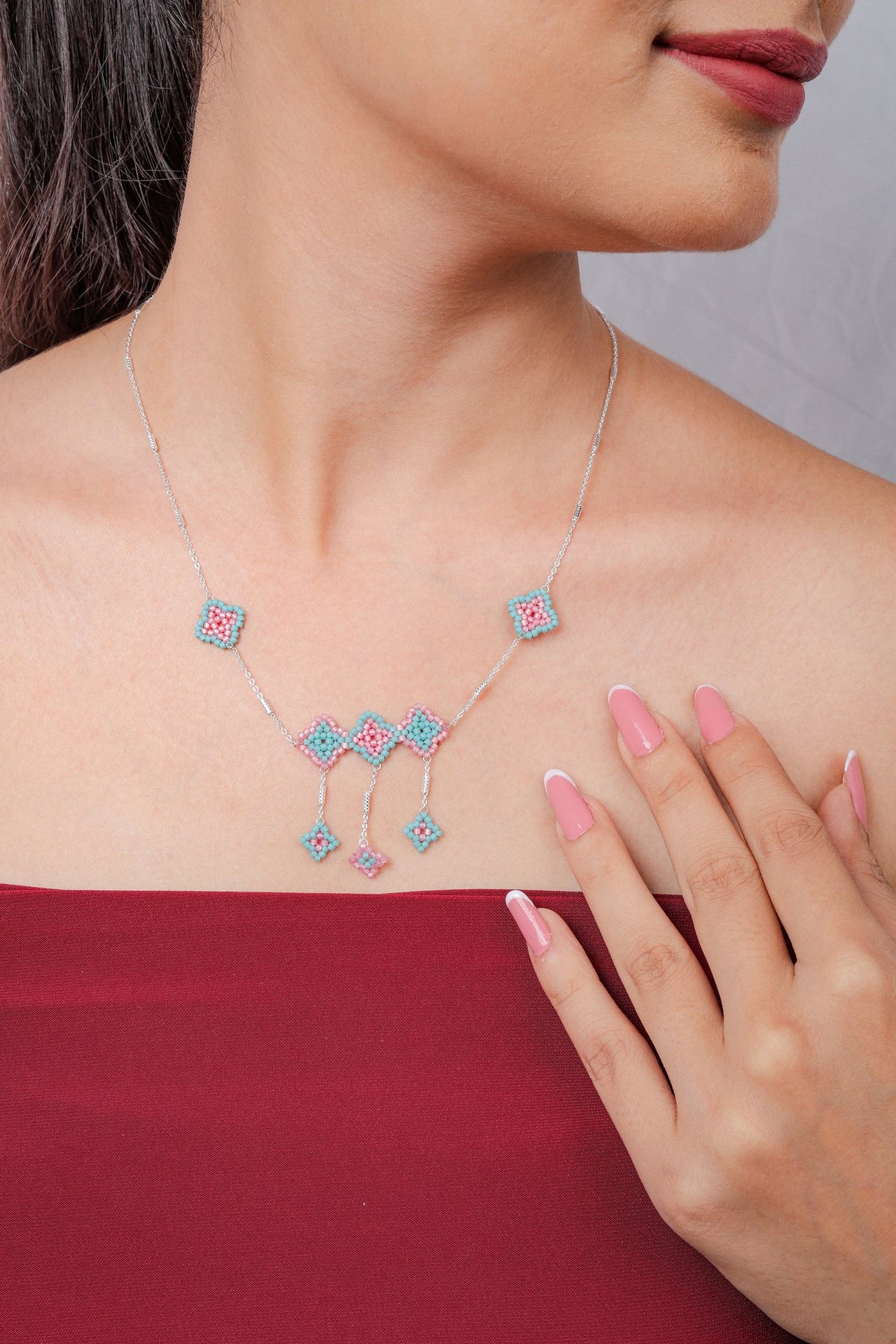 Silver necklace with aqua and pink beaded rhombus charms, a centre trio and three dangling drops