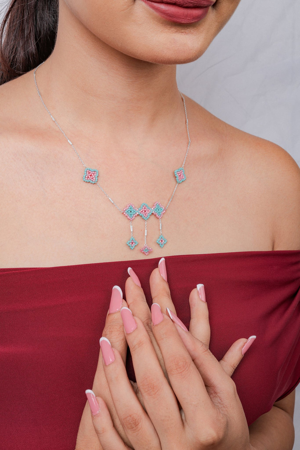 Model wearing silver chain with pink and aqua beaded rhombus cluster and drop charms