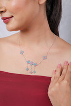Side view of model wearing silver necklace with aqua and pink rhombus charms and three drops