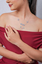 Model in red off-shoulder dress wearing delicate aqua and pink rhombus drop necklace