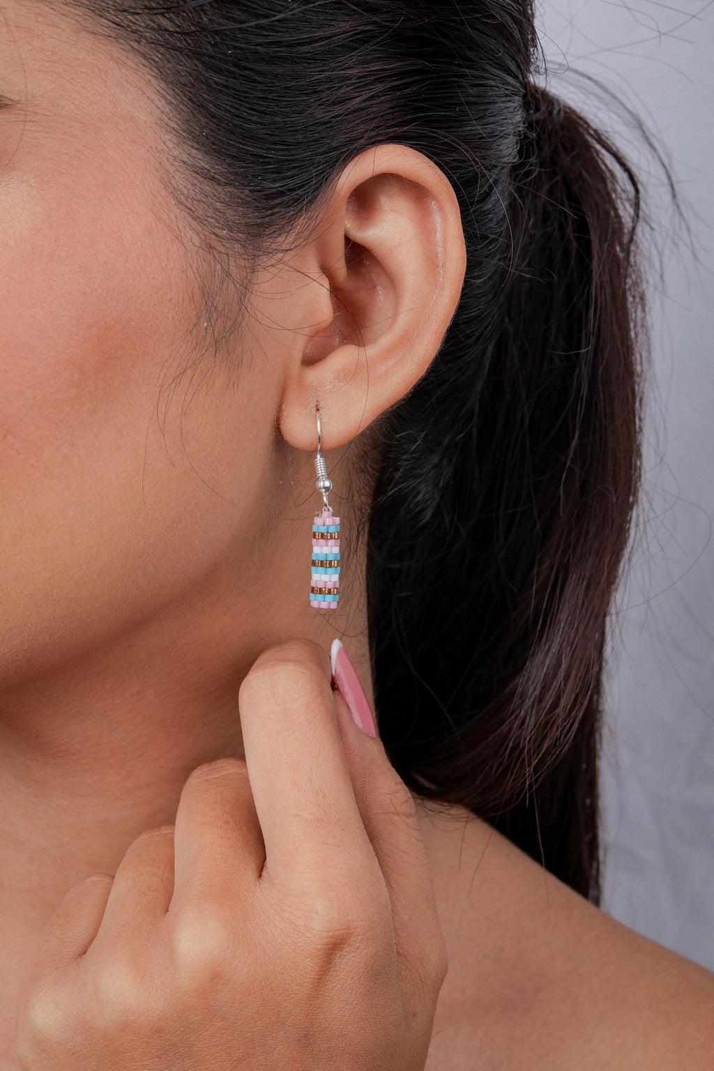 Close-up of striped pink, aqua and white beaded tube earring on a silver hook