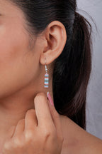 Close-up of striped pink, aqua and white beaded tube earring on a silver hook