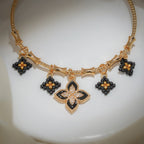 Close-up of black and gold beaded diamond charms around a crystal-studded black clover charm