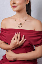 Model in off-shoulder top wearing black and gold beaded rhombus necklace