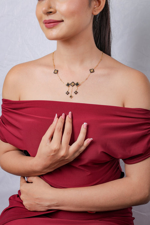 Model in off-shoulder top wearing black and gold beaded rhombus necklace