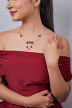Side view of model wearing black and gold geometric beaded drop necklace