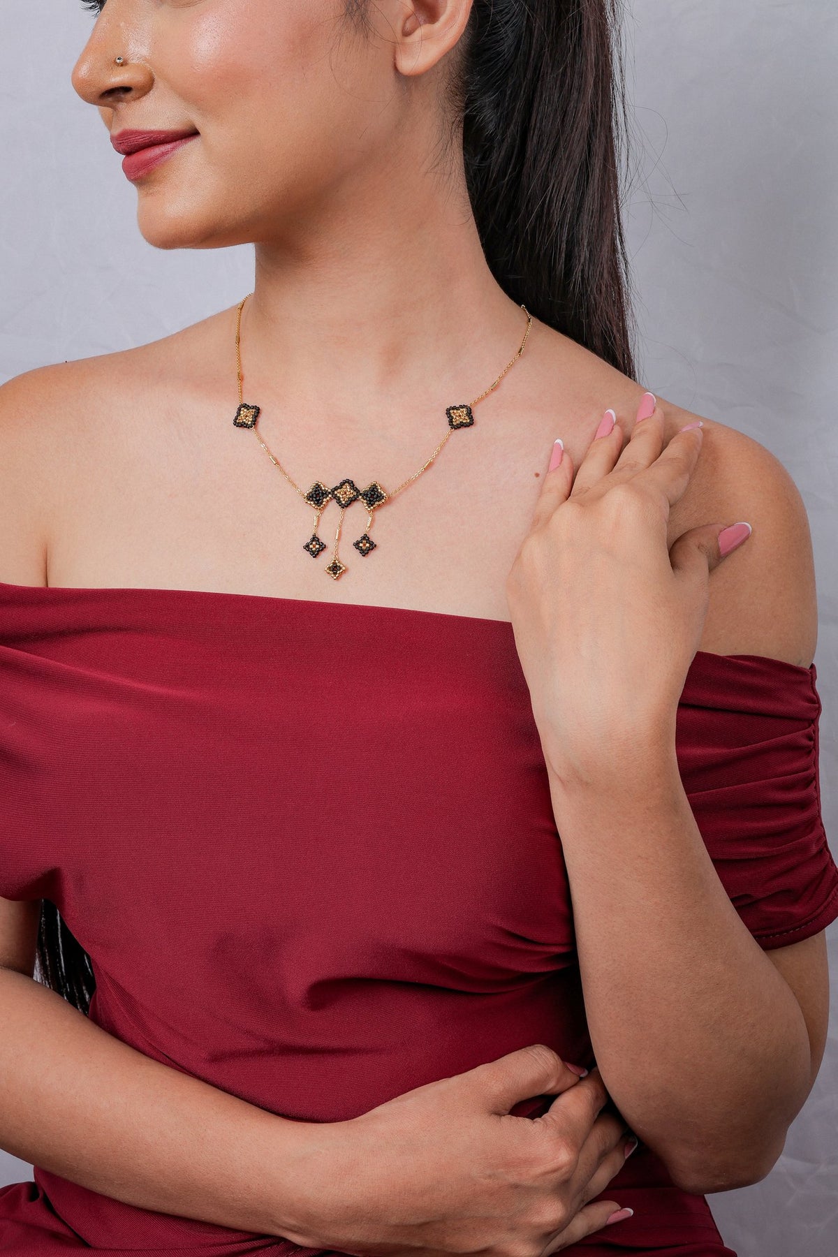 Side view of model wearing black and gold geometric beaded drop necklace