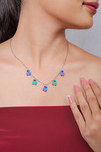 Silver chain necklace with five blue and turquoise beaded bird charms worn at the collarbone