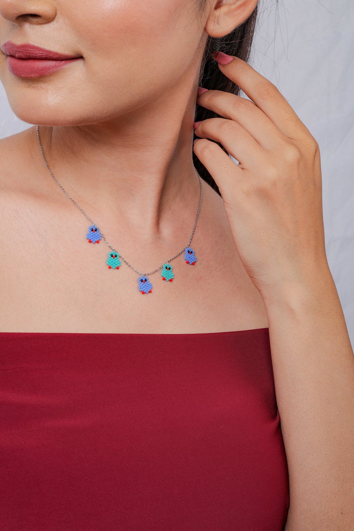 Side view of the silver necklace with little blue and turquoise beaded birds