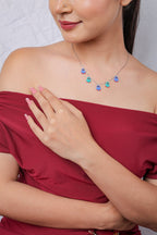 Model in a red off-shoulder top wearing the blue birdie charm necklace