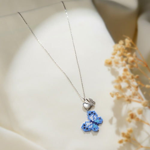 Silver chain necklace with a blue beaded butterfly pendant below a pearly heart and crystal butterfly