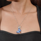 Model wearing silver necklace with blue beaded butterfly pendant against a black top