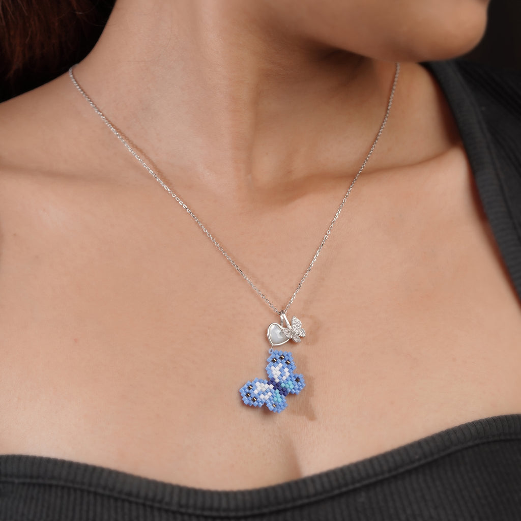 Angled view of blue butterfly pendant with pearly heart and crystal butterfly worn on model