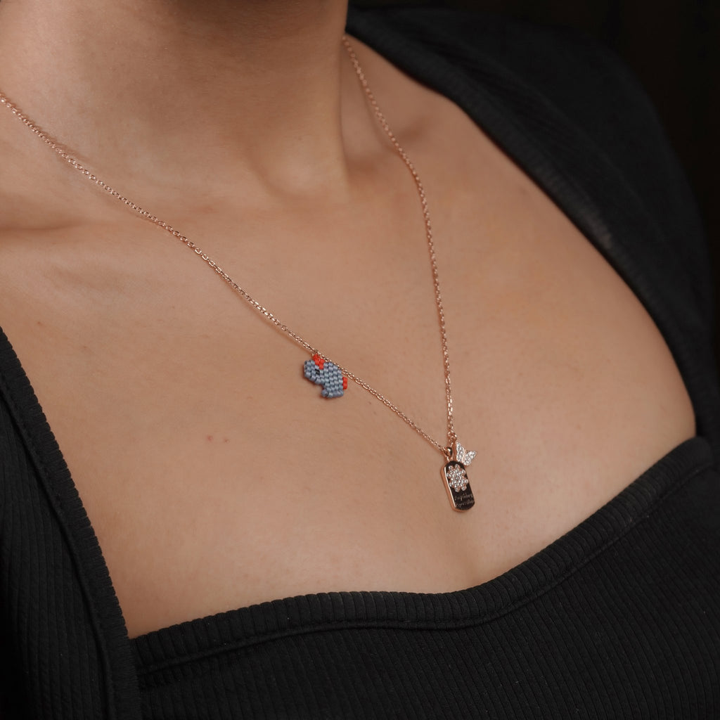 Model wearing the blue beaded elephant and crystal tag charm necklace on a rose-gold chain