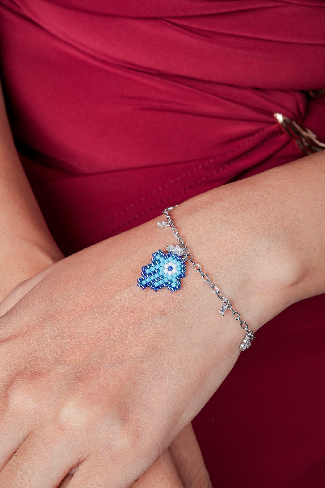 Silver tone chain bracelet with a blue beaded hamsa charm and small crystal drops