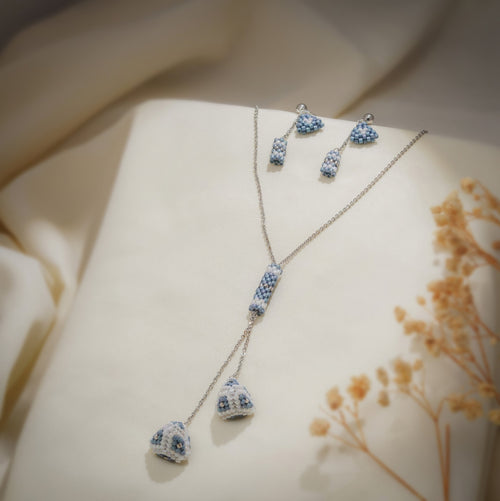 Silver lariat necklace with powder-blue beaded tube and pyramid drops beside matching earrings