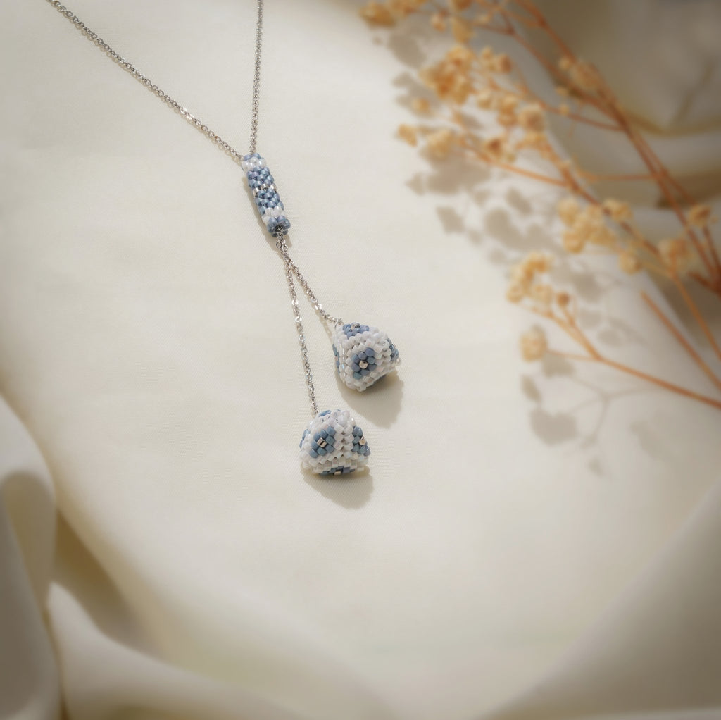 Close-up of powder-blue and white beaded tube bar and two pyramid drops on silver chain
