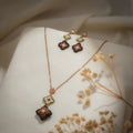 Rose-gold necklace with olive and bronze beaded clover drop and matching earrings on cream silk