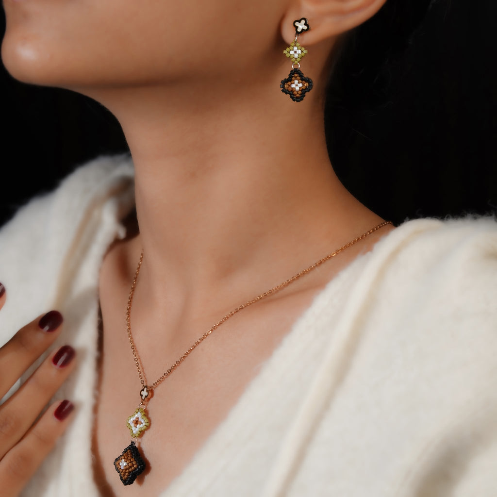 Model wearing the bronze and black beaded clover pendant with matching clover drop earrings