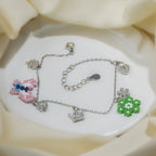 Silver charm bracelet with pink beaded butterfly, green beaded flower and crystal crown and heart charms