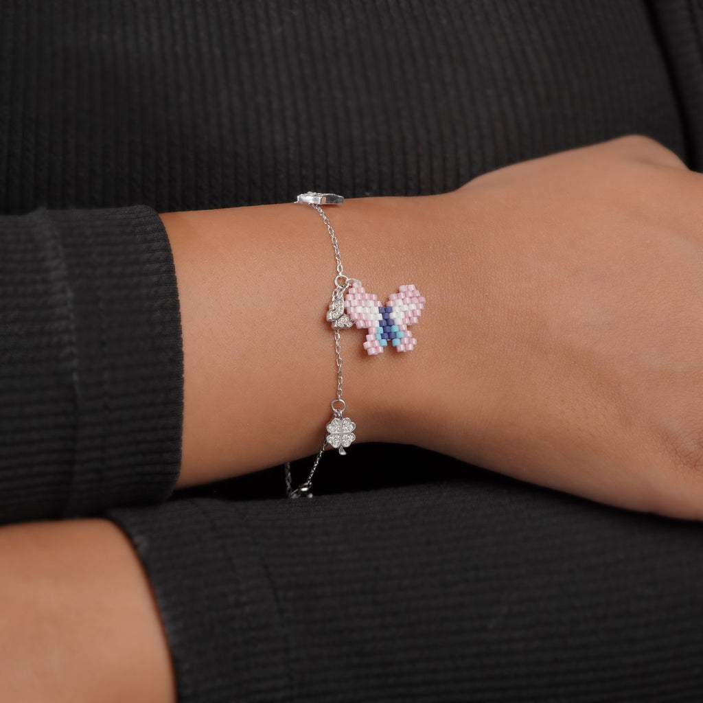Model wearing the silver charm bracelet with pink beaded butterfly and crystal clover charm