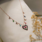 Close-up of beaded heart with red, blue and green centre beside butterfly and crystal drop charms