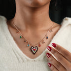 Model touching collarbone, wearing heart pendant necklace with butterflies and colourful crystals