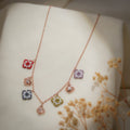 Rose-gold charm necklace with red, lilac, grey and olive beaded squares and filigree butterflies on cream silk