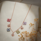 Rose-gold charm necklace with red, lilac, grey and olive beaded squares and filigree butterflies on cream silk