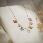 Beaded square and crystal butterfly charm necklace draped over cream fabric with dried flowers