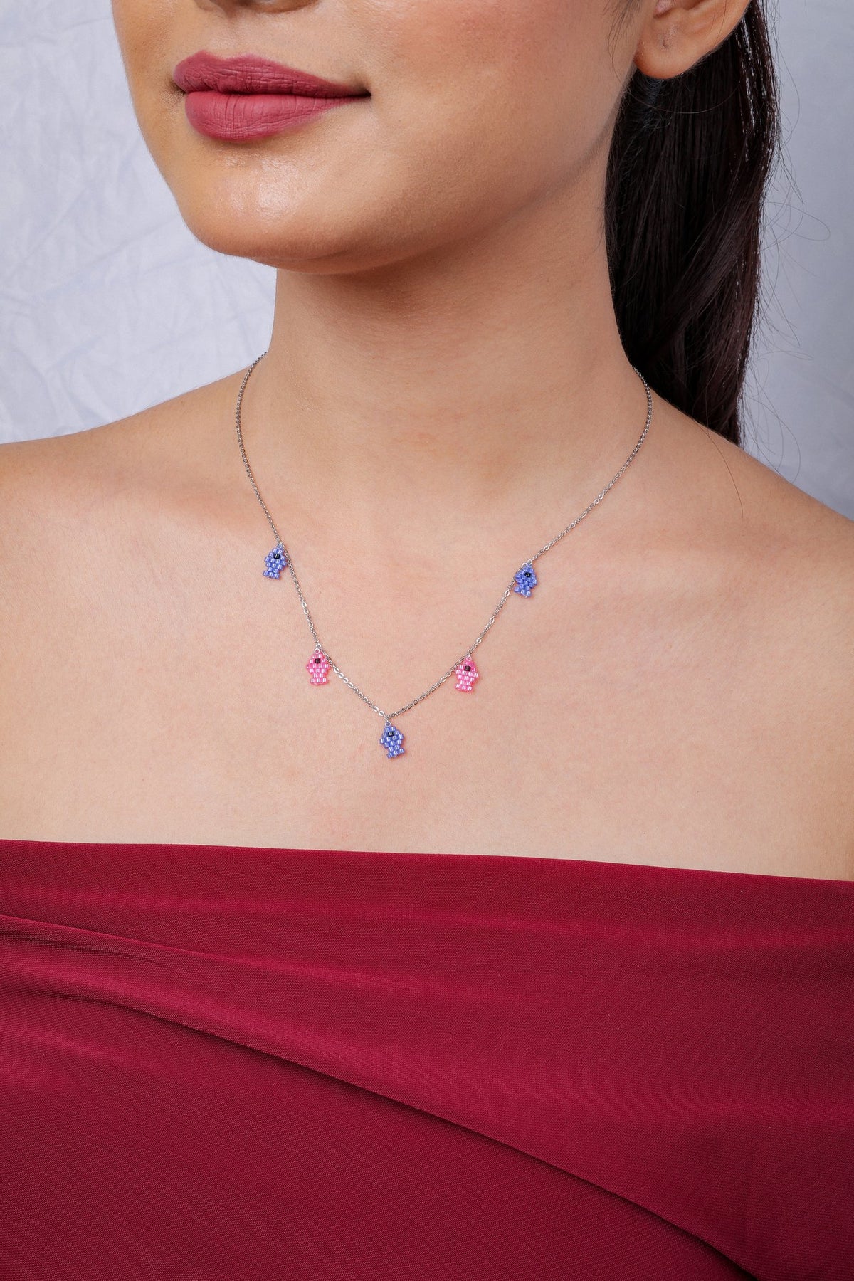 Silver-tone chain with five tiny beaded fish charms in periwinkle blue and pink on a model