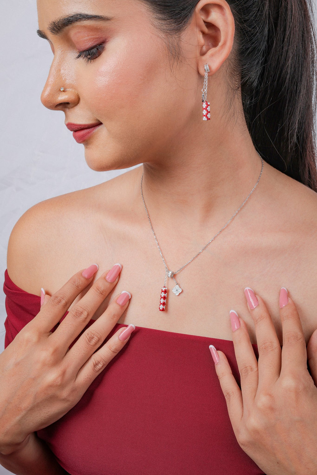 Model wearing silver necklace with red and white beaded tube pendant and matching drop earring