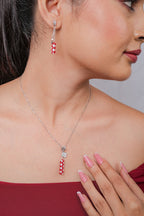 Profile of model wearing red and white beaded tube pendant and matching chain drop earring