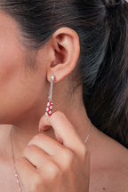 Close view of crystal stud earring with fine chain drops and red and white beaded tube