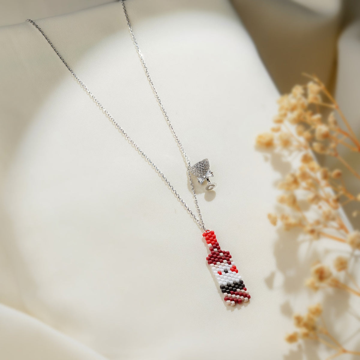Silver chain necklace with a red and white beaded bottle charm and crystal cocktail glass charm