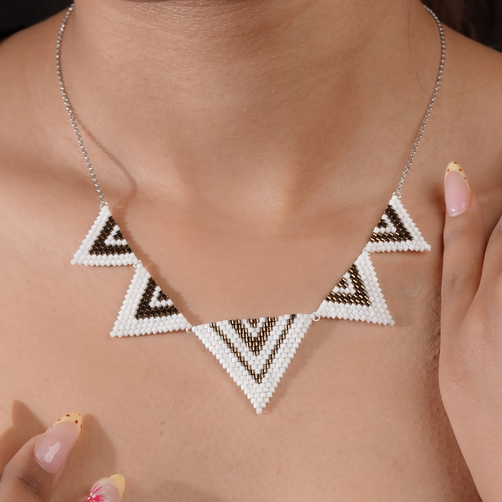 Close-up of beaded triangle necklace on the model's collarbone, larger triangle at the centre