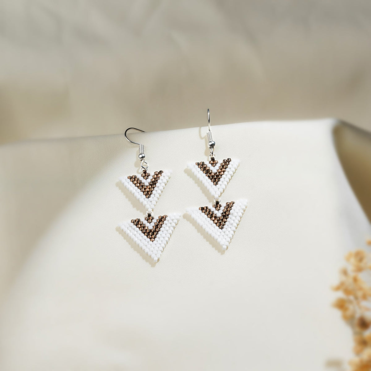 Pair of double-triangle beaded drop earrings in white and brown on silver hooks