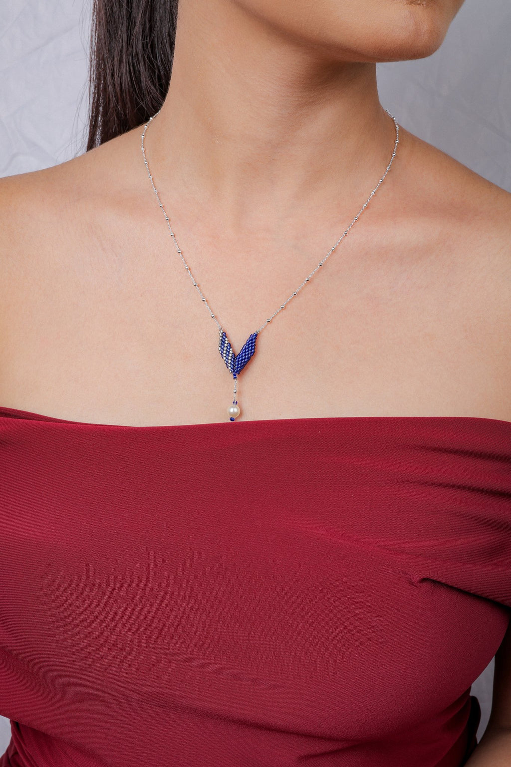 Silver satellite chain with a cobalt and silver beaded V-shaped pendant and pearl-look drop