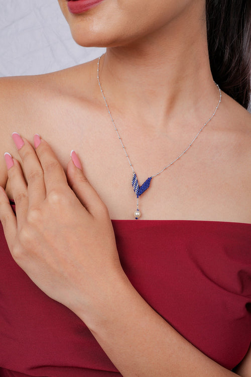 Model wearing cobalt chevron pendant with pearl-look drop on a fine silver chain