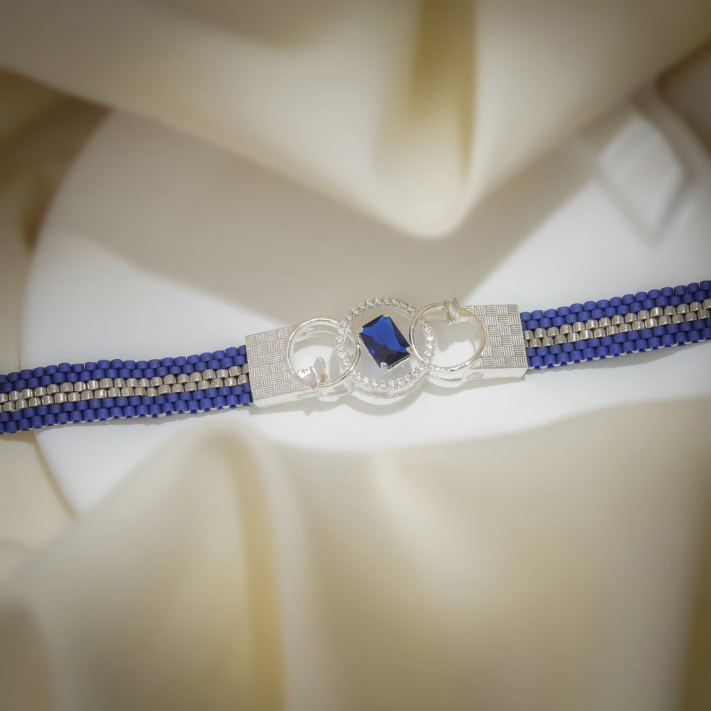 Cobalt and silver woven bead bracelet with crystal-set interlocking-ring centrepiece on cream fabric