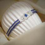 Cobalt loom bracelet draped over a ribbed white stand, showing the silver stripe and clasp end