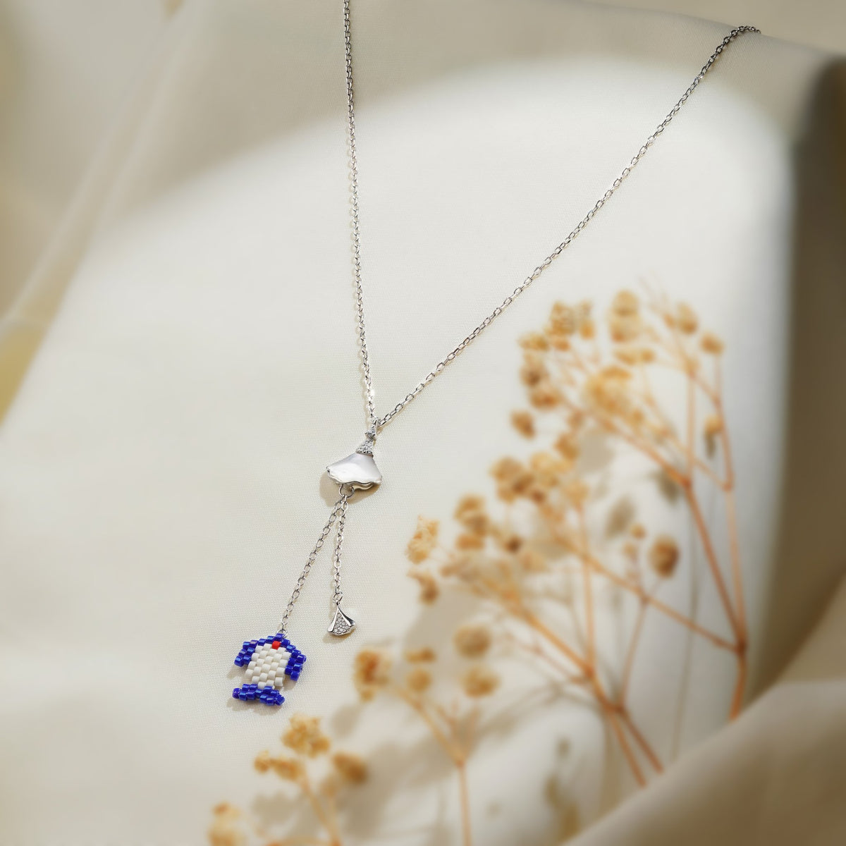 Silver lariat necklace with pearly fan connector, cobalt and white beaded charm and crystal drop