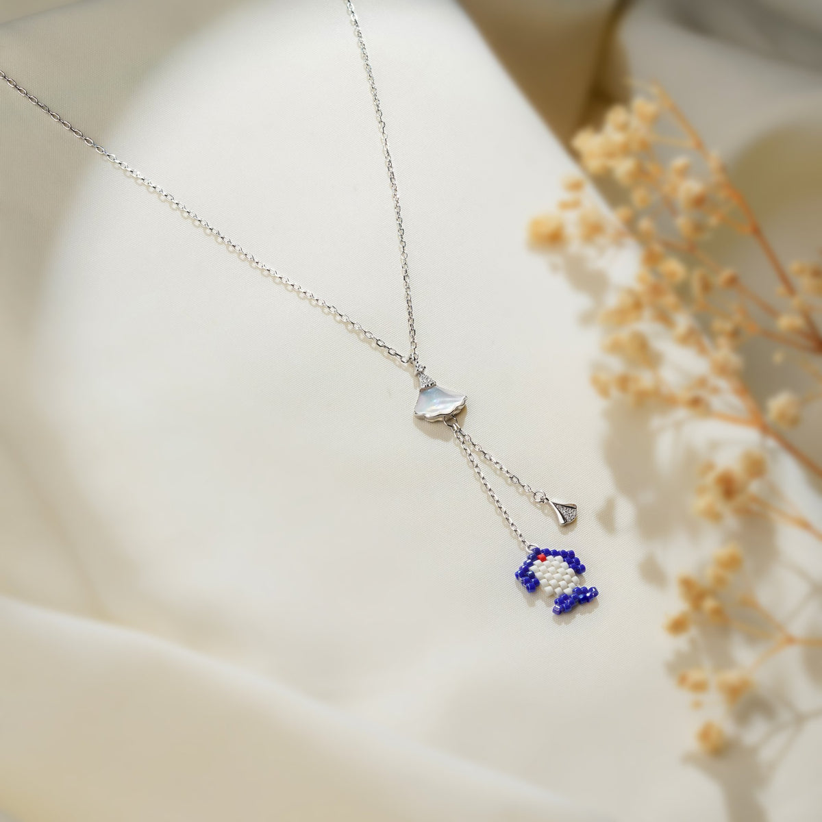 Close-up of cobalt and white beaded charm and pavé fan drop hanging from pearly white connector