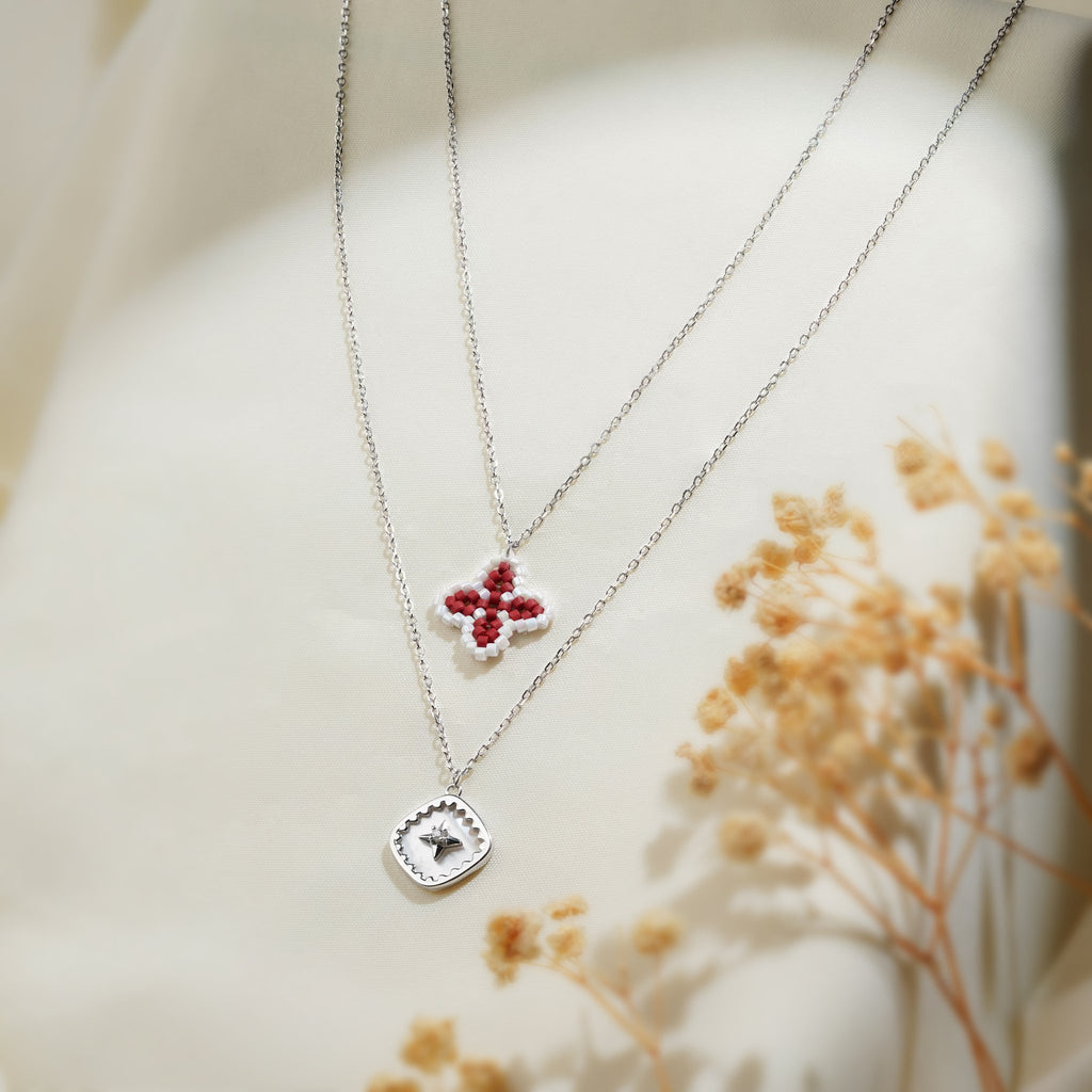 Two-tier silver-tone necklace with a red beaded clover and a pearly square star pendant