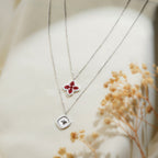 Two-tier silver-tone necklace with a red beaded clover and a pearly square star pendant
