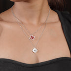 Model wearing a layered silver-tone necklace with red clover and star pendants