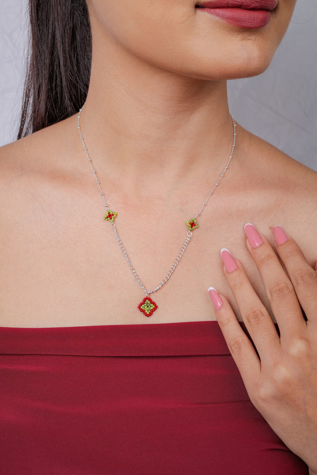Silver chain necklace with red and lime beaded diamond pendant and two small diamond stations