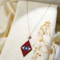 Rose-gold-tone chain with a sunburst eye connector and a red beaded rhombus evil-eye pendant